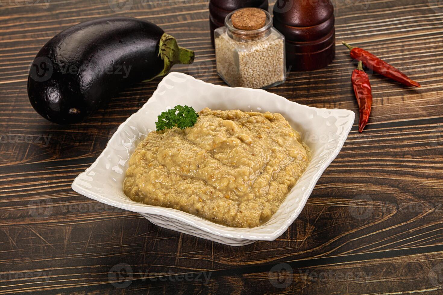 A bowl of hummus with an eggplant and spices photo