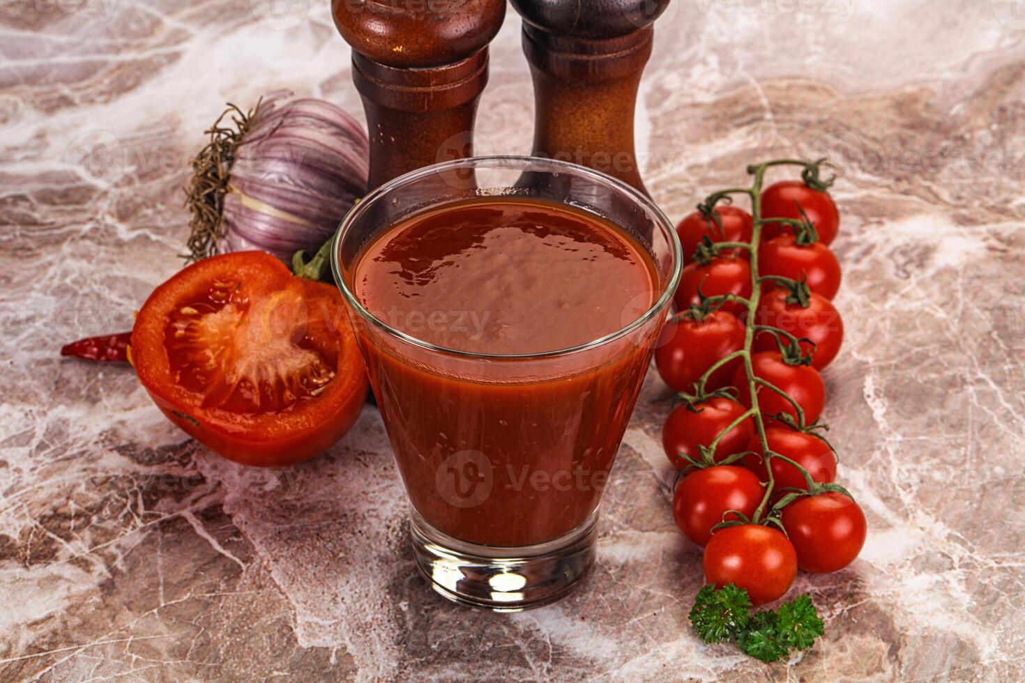 A glass of tomato juice next to a pepper and a tomato photo