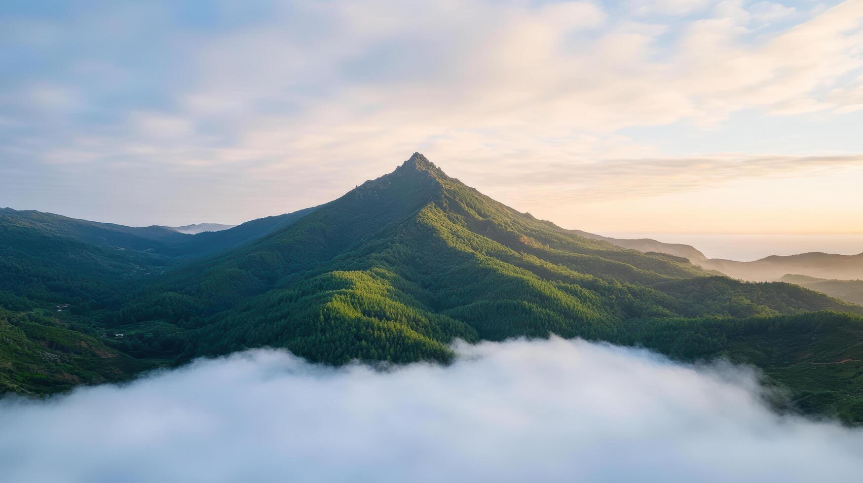 Majestic mountain peak surrounded by lush greenery and mist, glowing in golden hour light photo