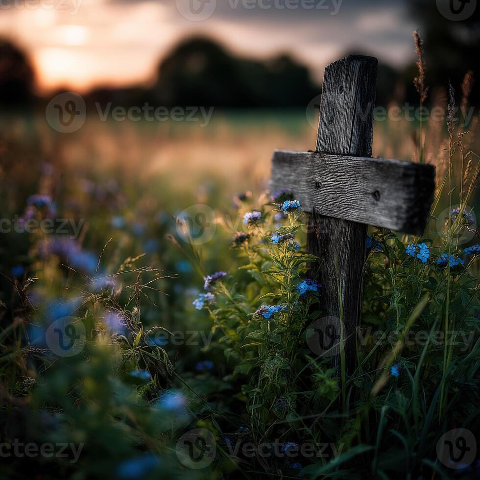 Wooden cross surrounded by wildflowers at sunset in a field photo