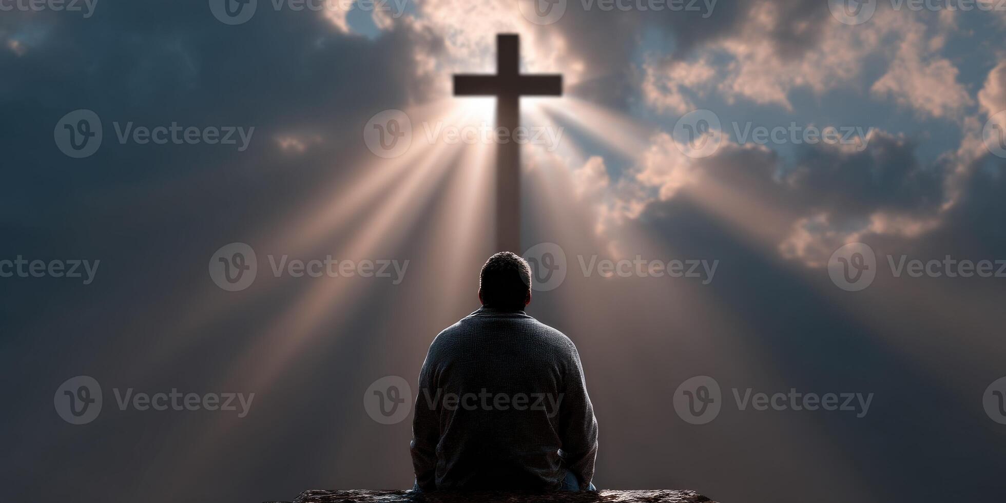 Person reflecting under a cross with radiant light in the sky photo