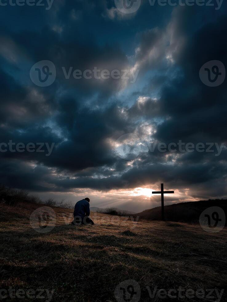 A man sits on the hill with a cross in the background photo