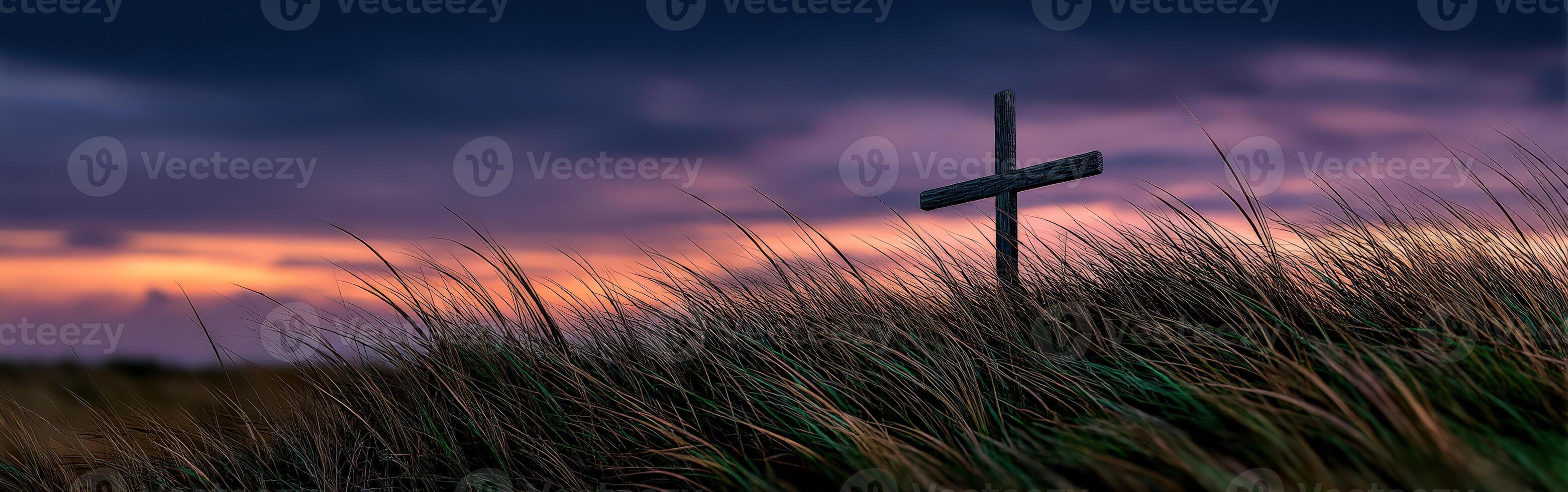Cross stands tall in grassy field during sunset photo