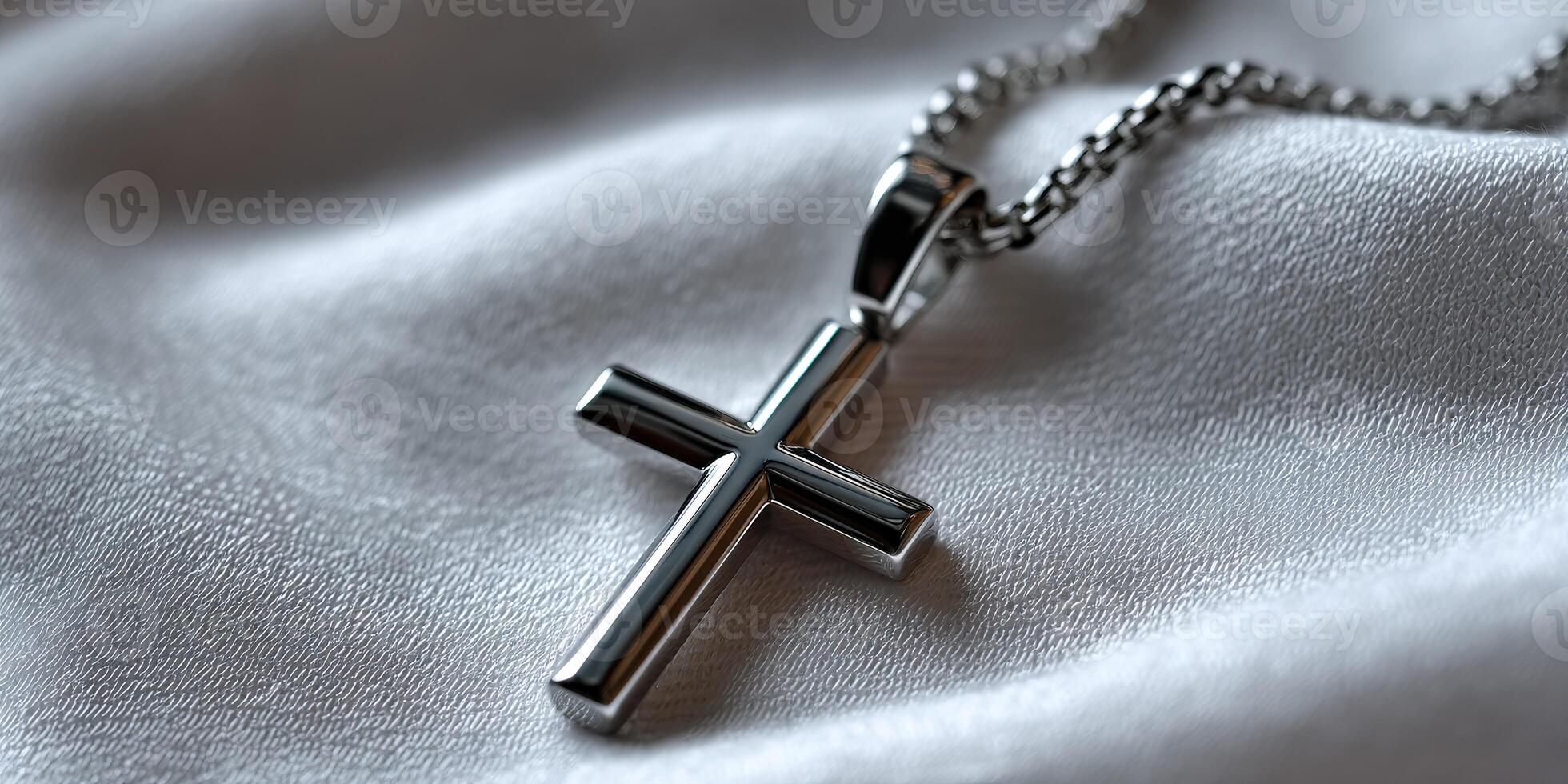 A silver cross necklace laying on a white cloth photo