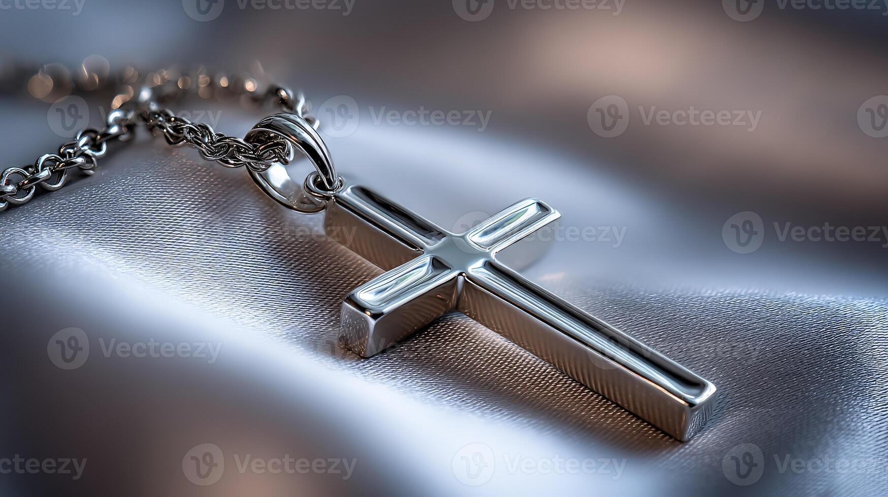 Silver cross pendant resting on satin fabric in soft lighting photo