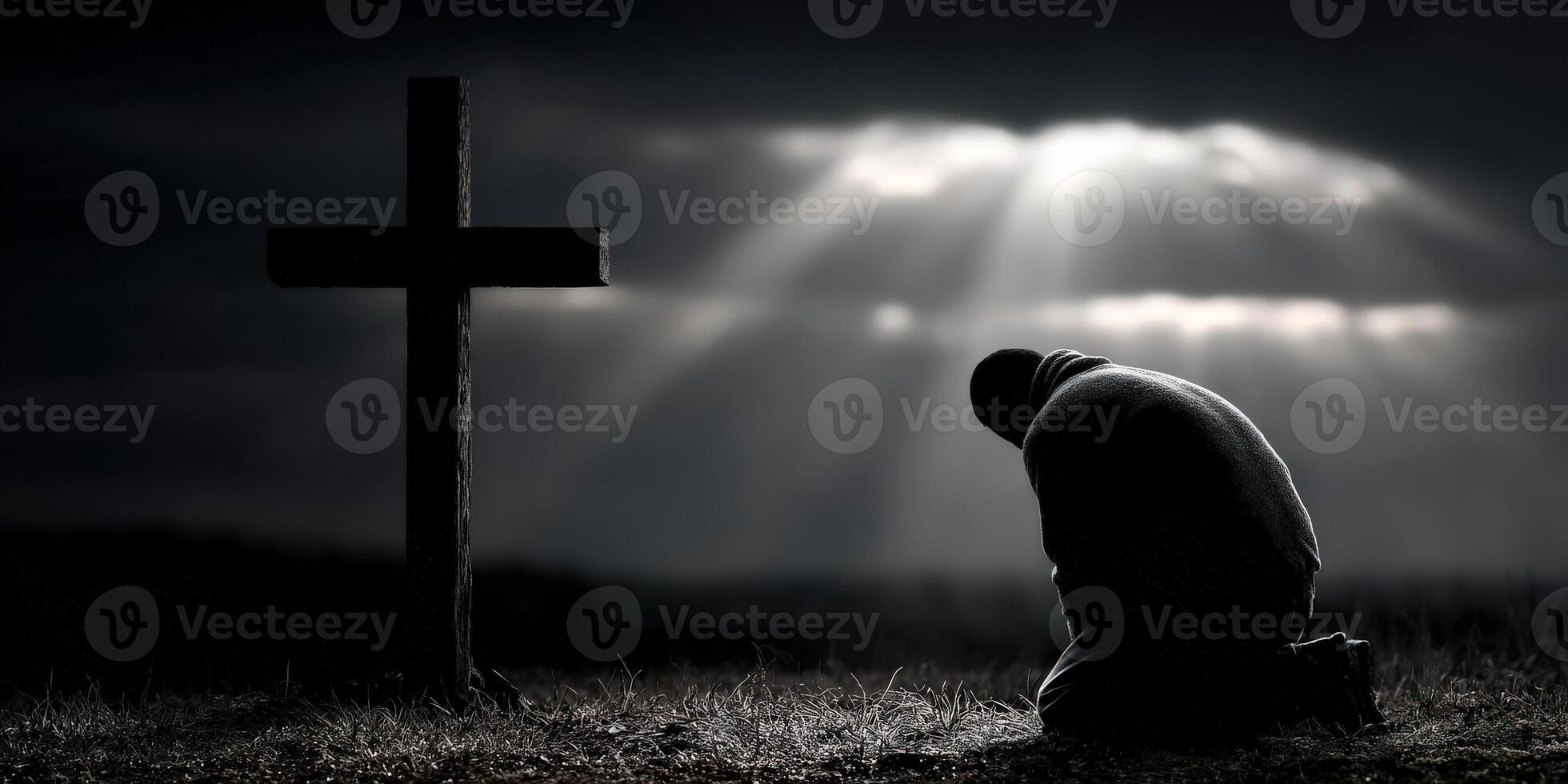 A man kneels down in front of a cross photo