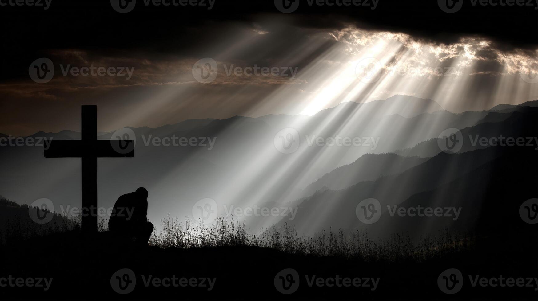 Man kneeling beside cross in serene mountain landscape photo