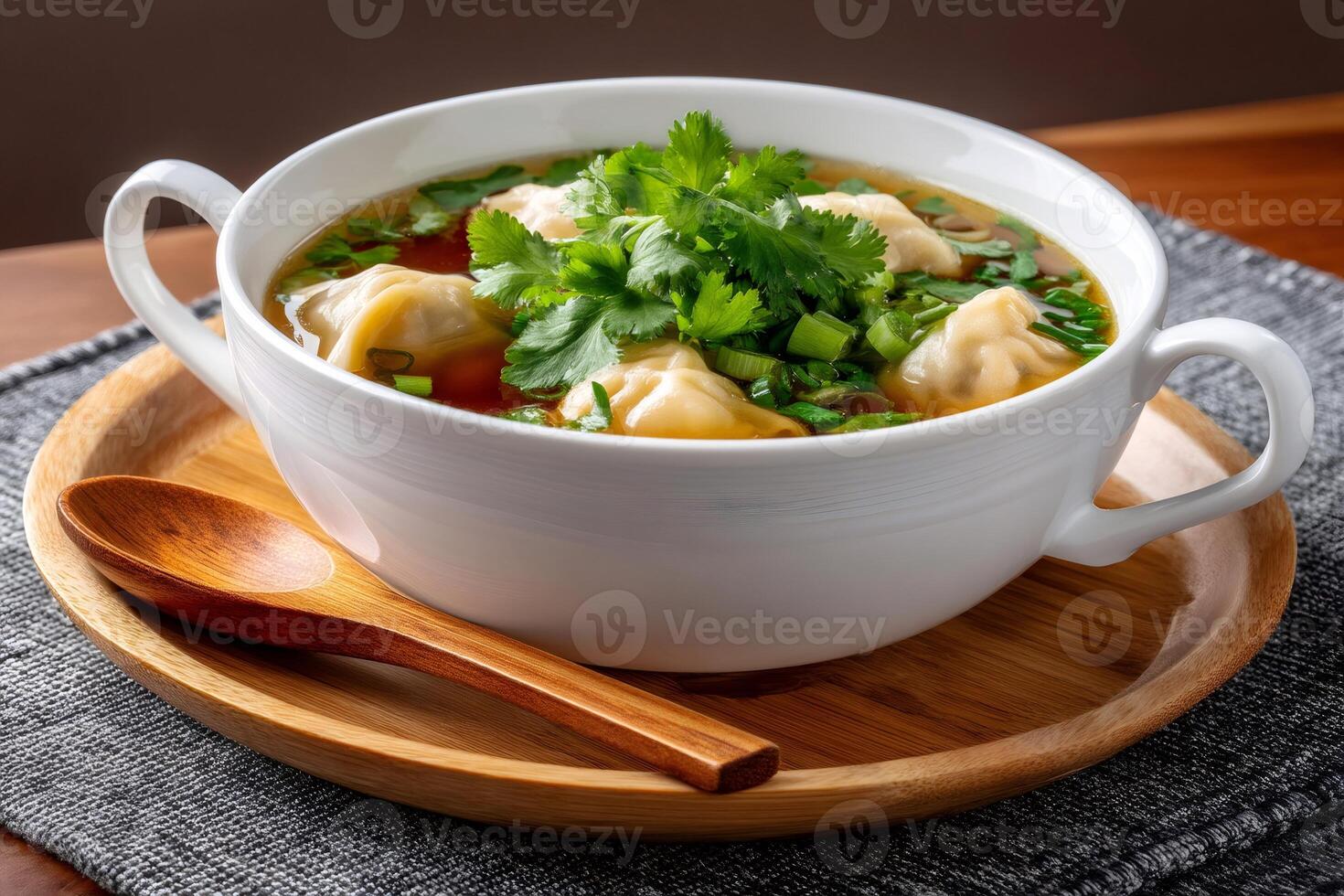 Steaming wonton soup with fresh coriander and green onions served in white bowl photo