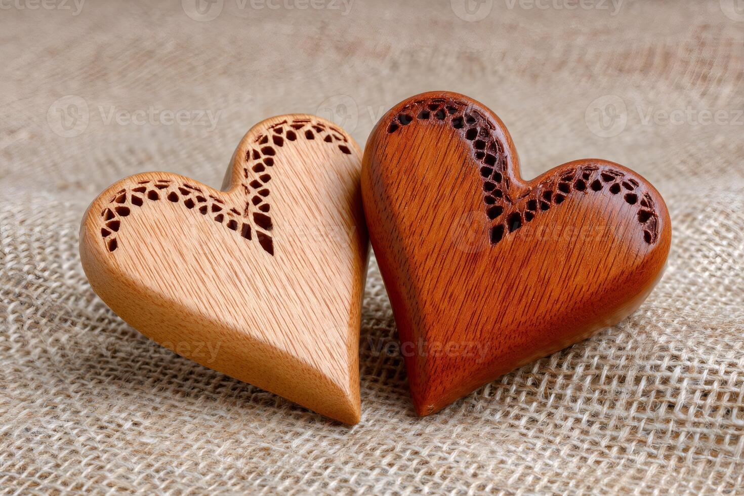 Two wooden hearts showing love and affection are laying on a burlap background photo