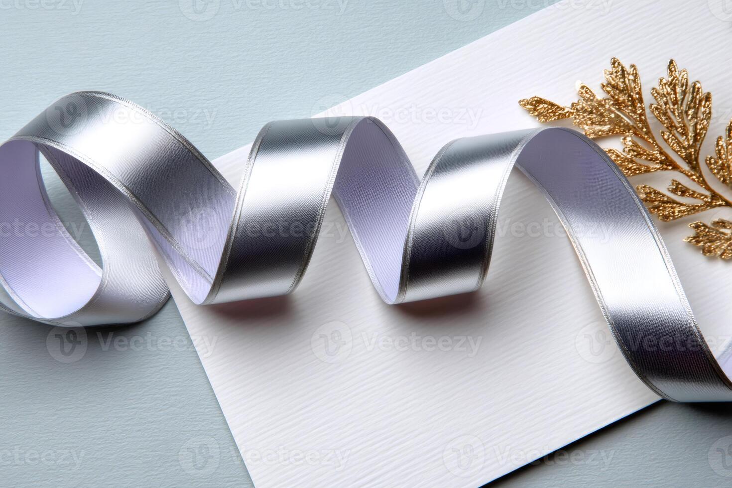 Silver ribbon swirling on white card with golden decoration photo