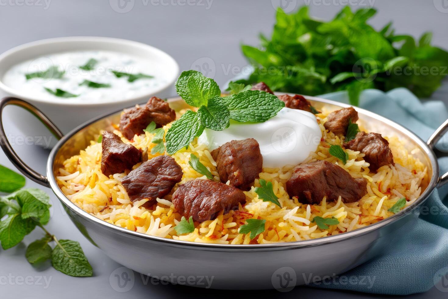 Delicious mutton biryani garnished with mint and yogurt in a traditional Indian metal pot photo