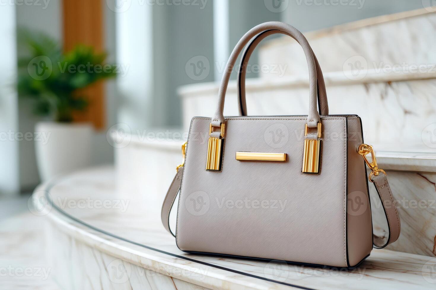 Elegant beige leather handbag with golden details sitting on marble steps photo