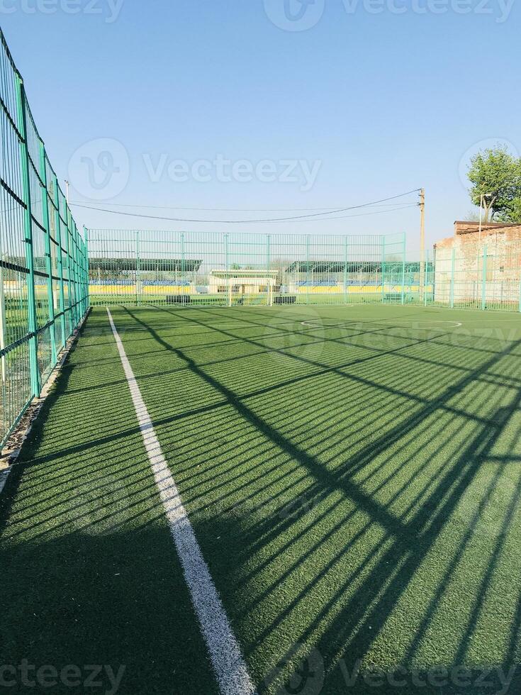 Green artificial turf soccer field with clear blue sky backdrop photo