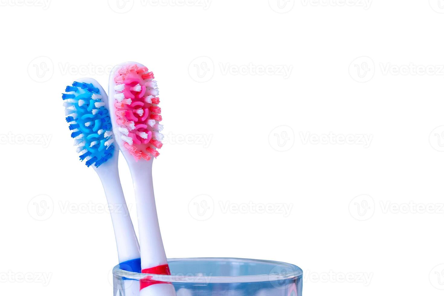 Two colorful toothbrushes in glass cup on white background photo