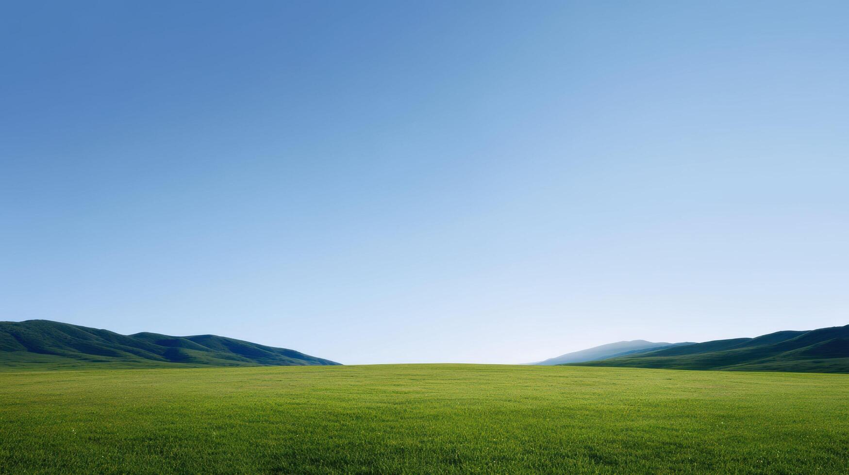 Green field with distant mountains under clear blue sky, featuring vibrant grassy landscape, bright daylight, peaceful scenery, and refreshing natural atmosphere stretching across horizon. photo