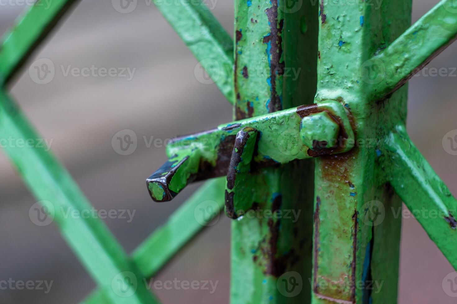 Close-up of weathered green metal gate with rusty latch and textured surface photo
