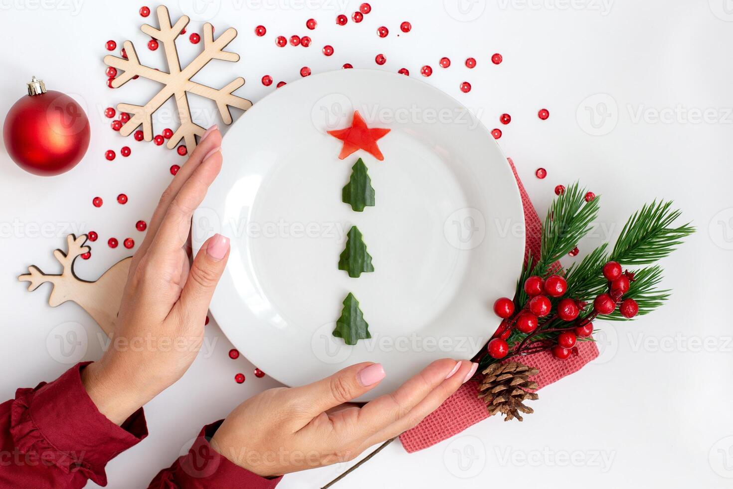 New Year's table decor. Female hands hold a plate with a cucumber snack in the form of a Christmas tree photo