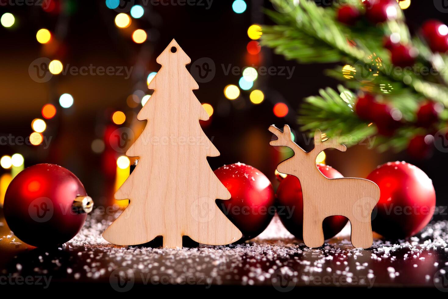 Wooden toy deer and spruce on a dark table with white snow and red ball. photo
