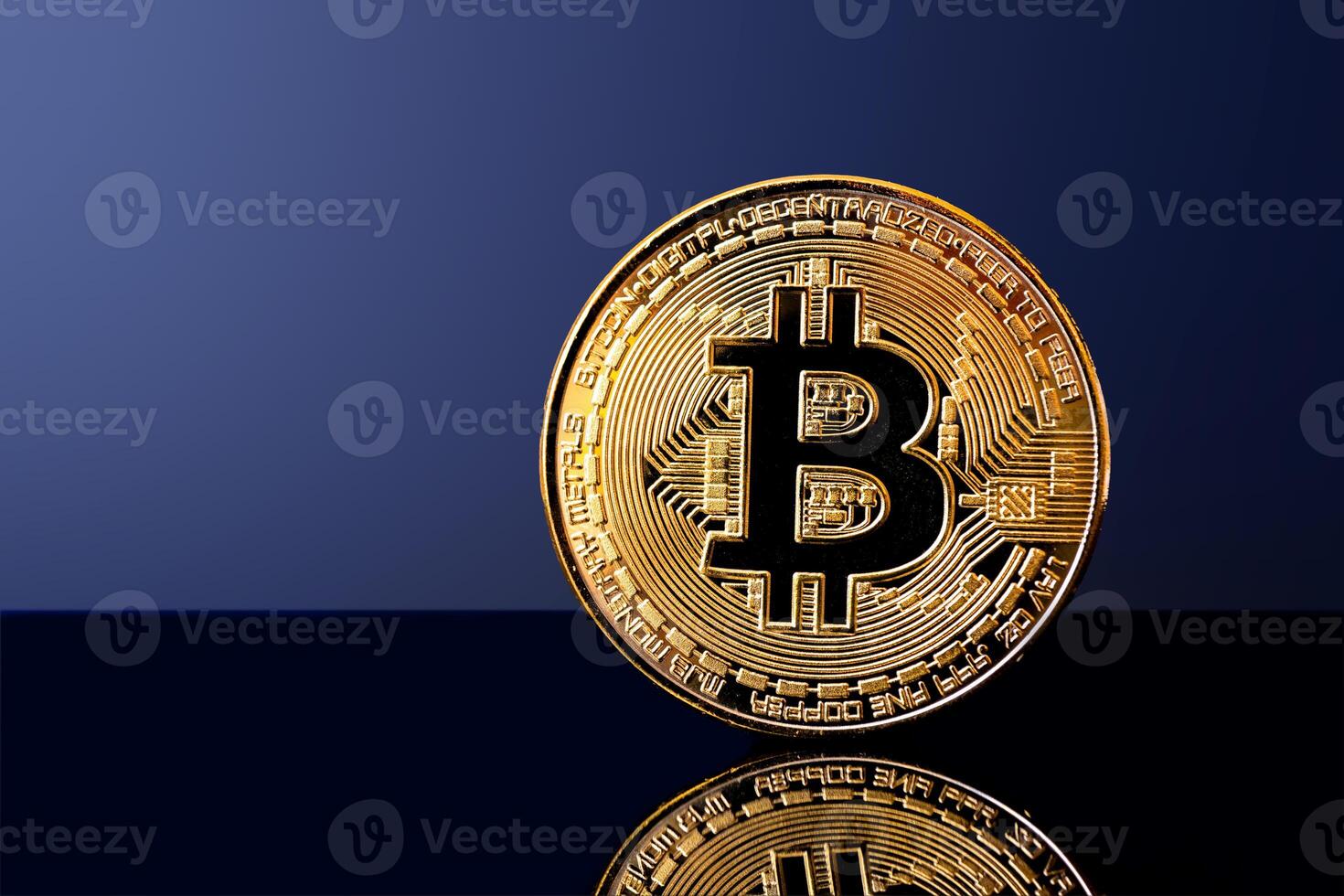 Shiny bitcoin coin on reflective surface with dark blue background photo