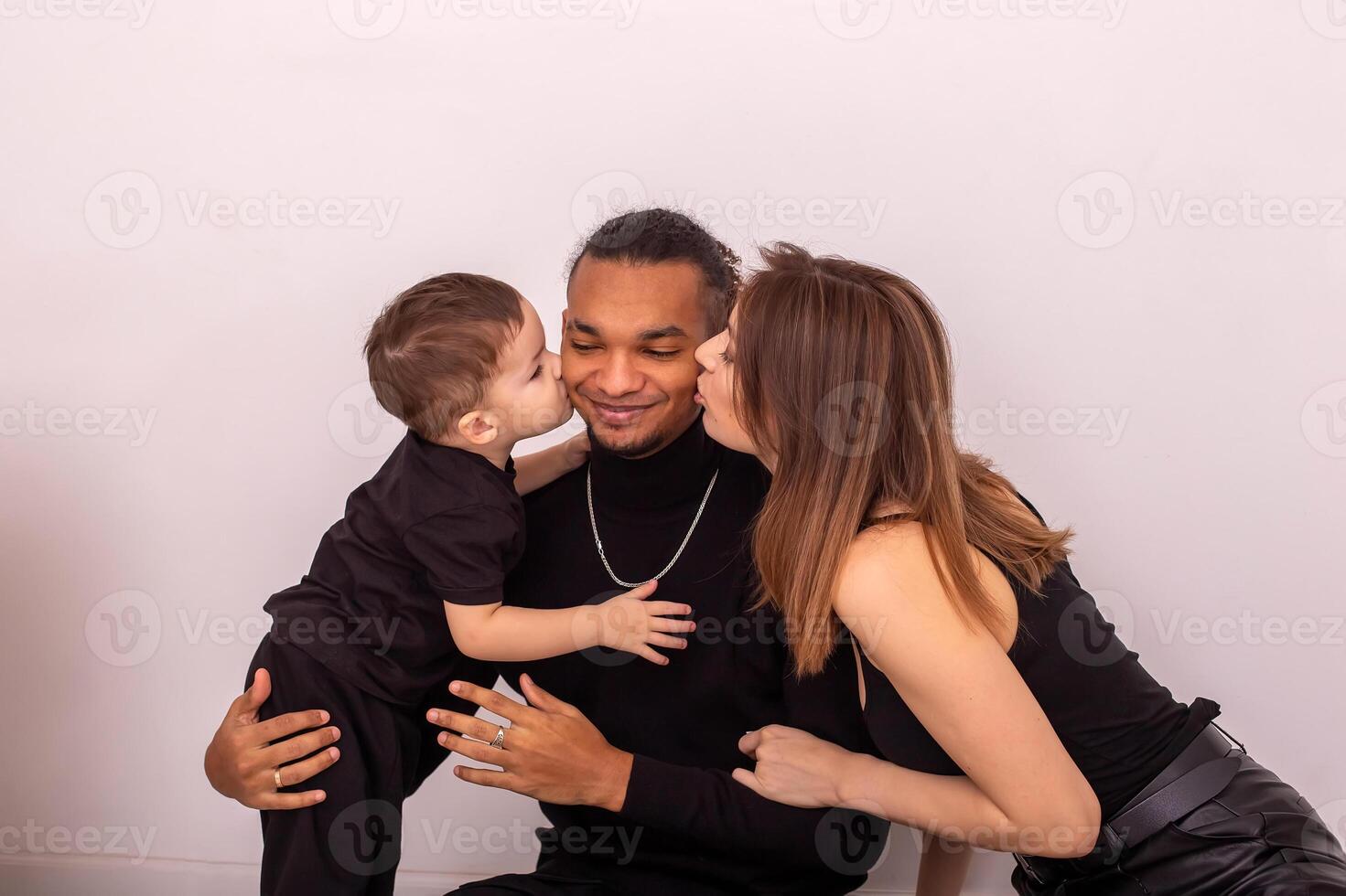 a woman and little boy, kiss a stylish young man on both sides on the cheeks photo