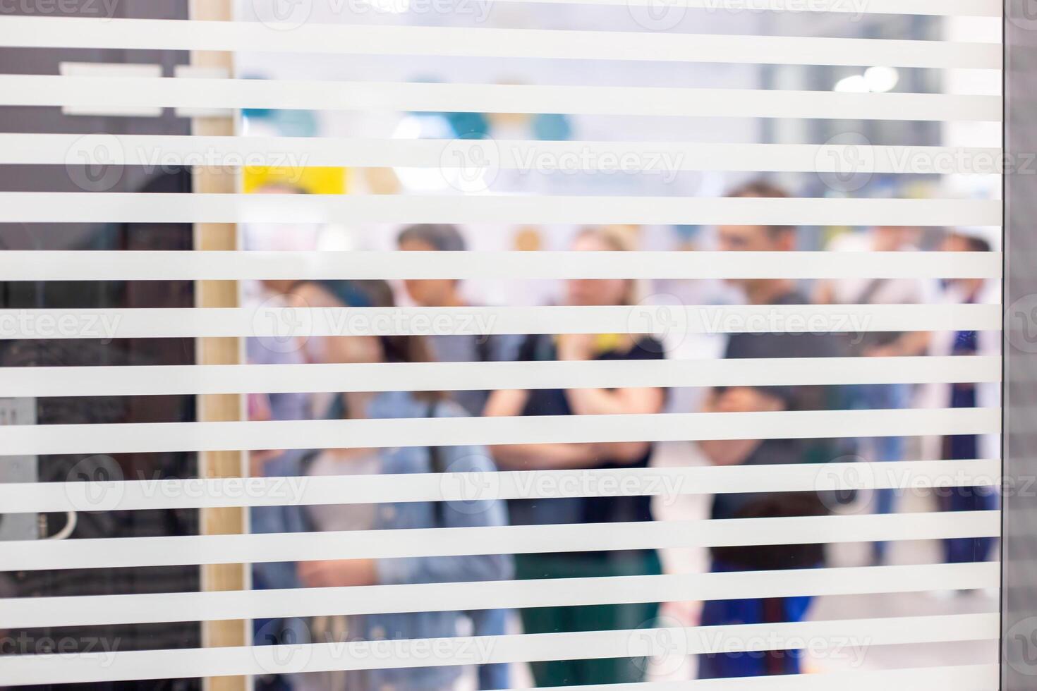 Blurred figures of people seen through the slats of window photo