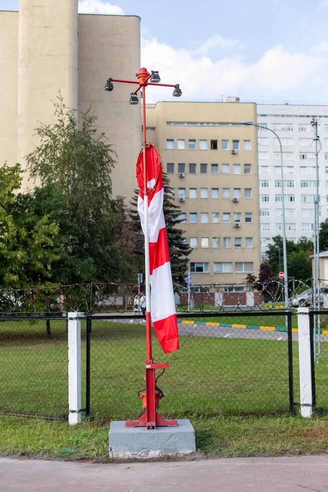 Moscow, Moscow region, Russia - 03.09.2023.A striped wind direction indicator wrapped around its pole on the airfield with buildings in the background photo