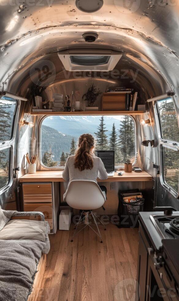 Female adult working on laptop in camper van office with mountain view photo