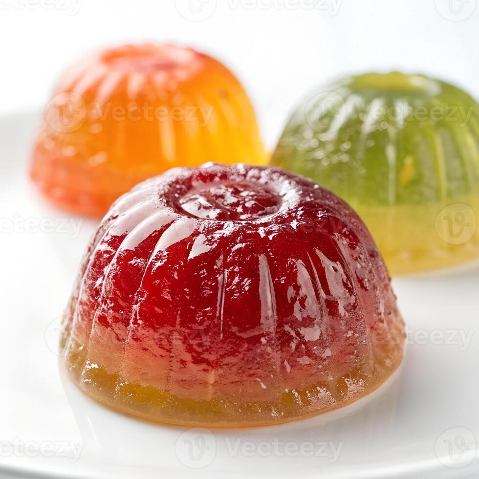 Three colorful jelly desserts, one red, one orange and one green, on a white plate, in a studio photo