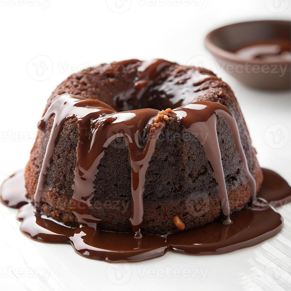 Chocolate cake with chocolate syrup on a white plate, with a bowl of chocolate syrup in the background photo