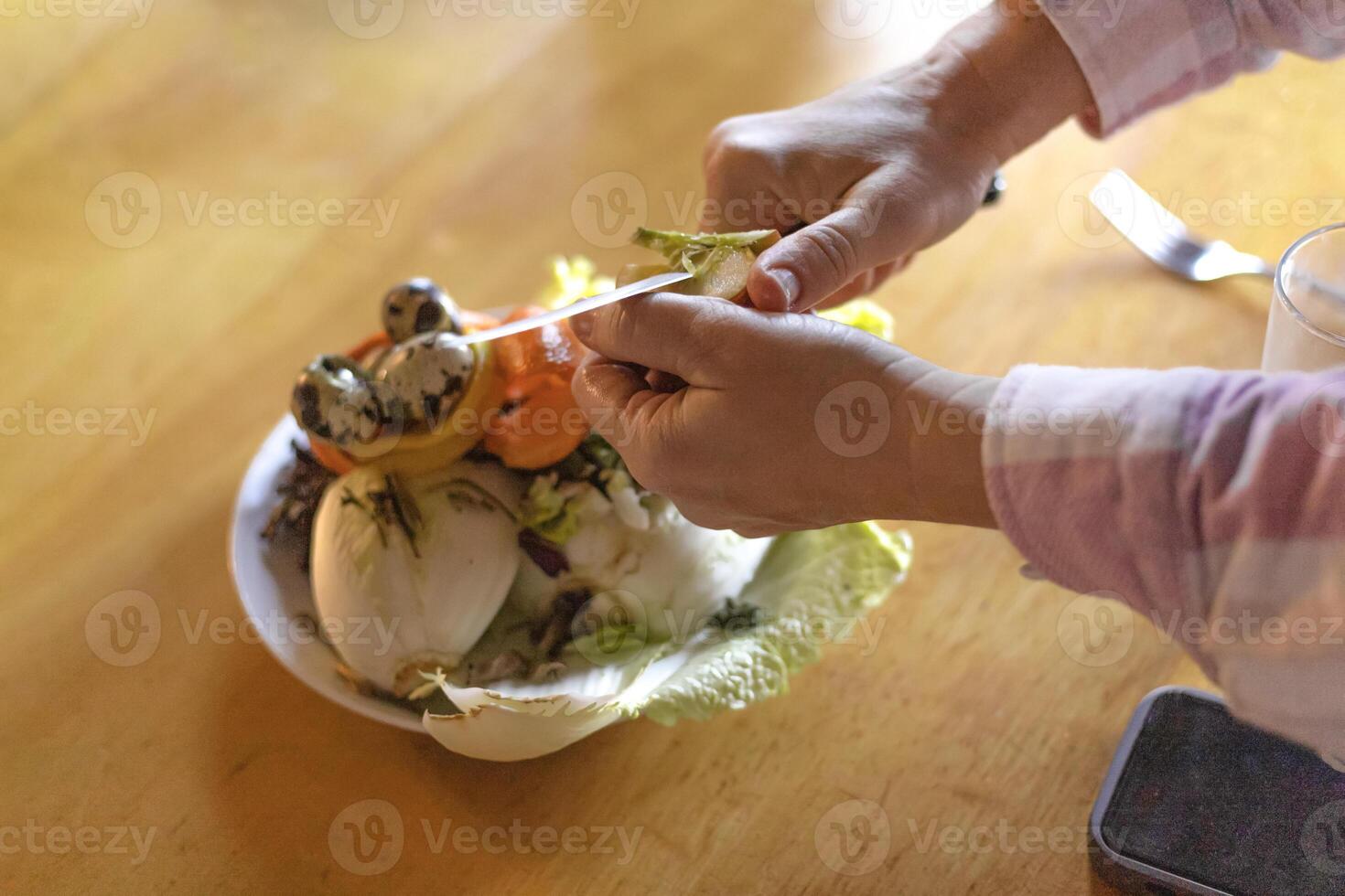 female hands peeling an apple over a food waste container photo