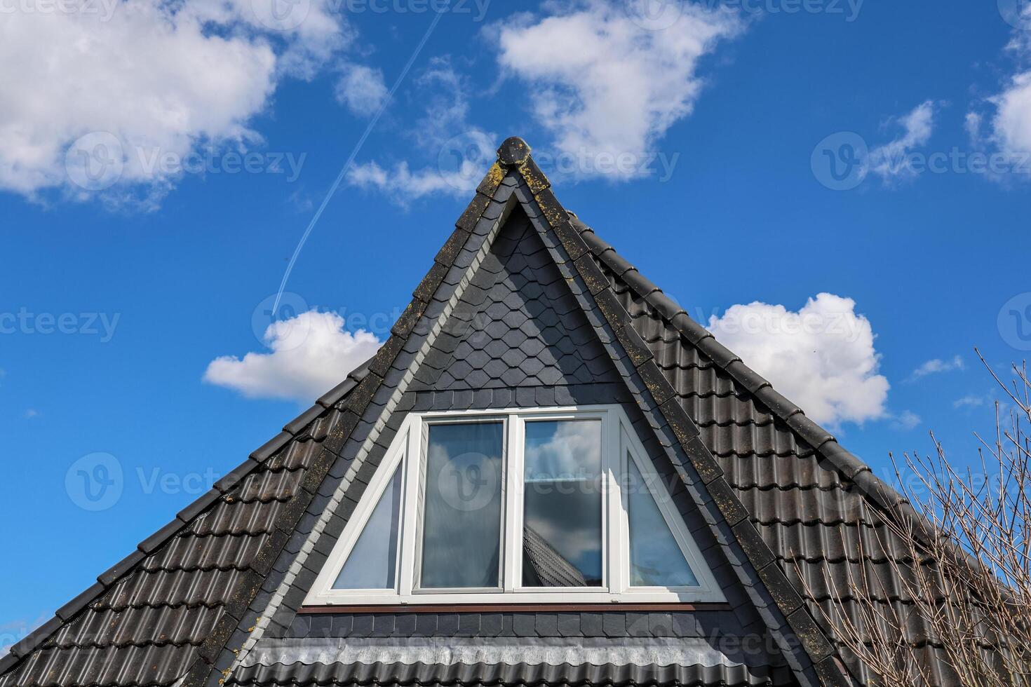 Triangular dormer window is illuminating the attic of a modern house photo