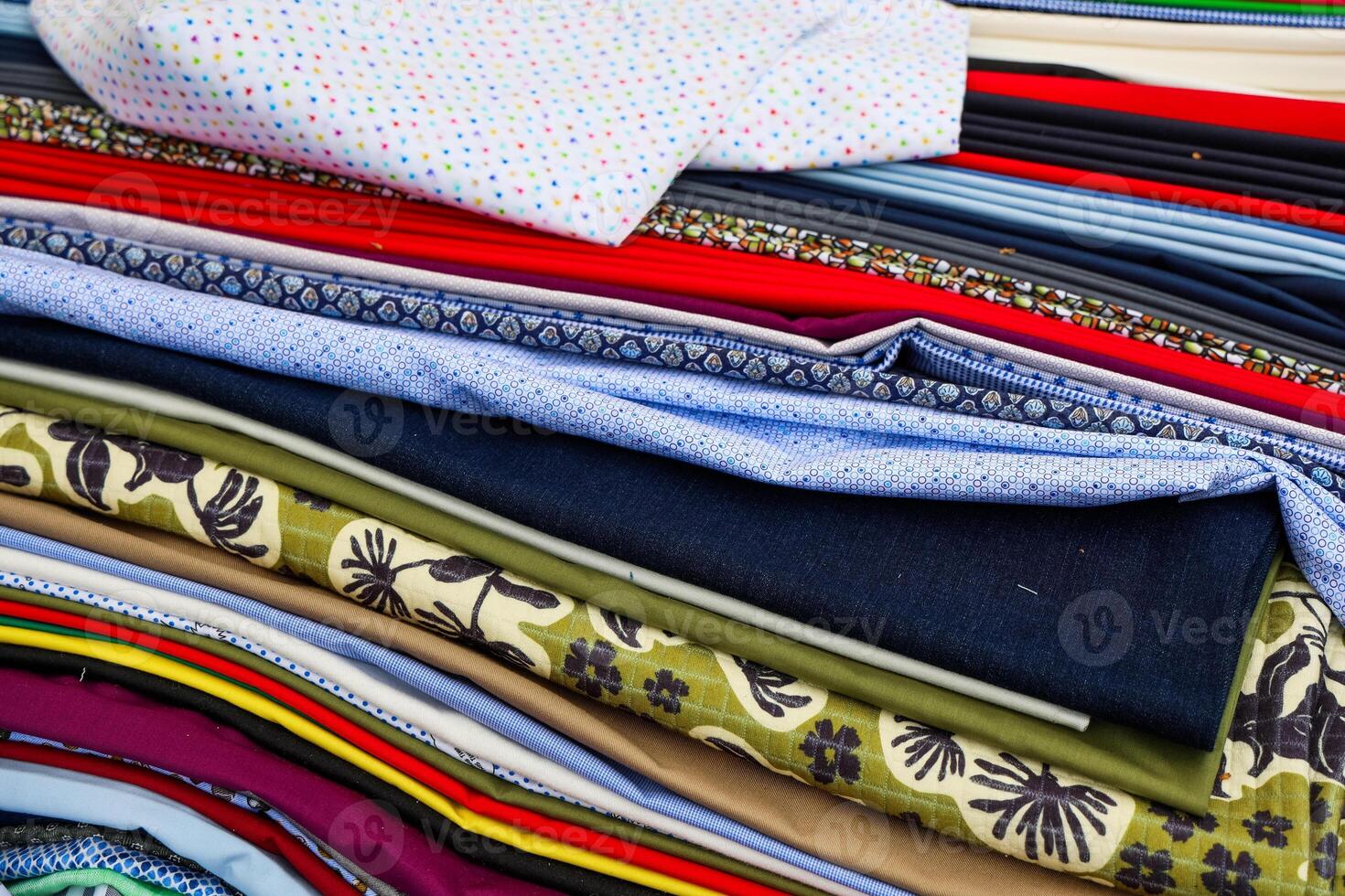 Stack of colorful fabrics showing various patterns and textures photo