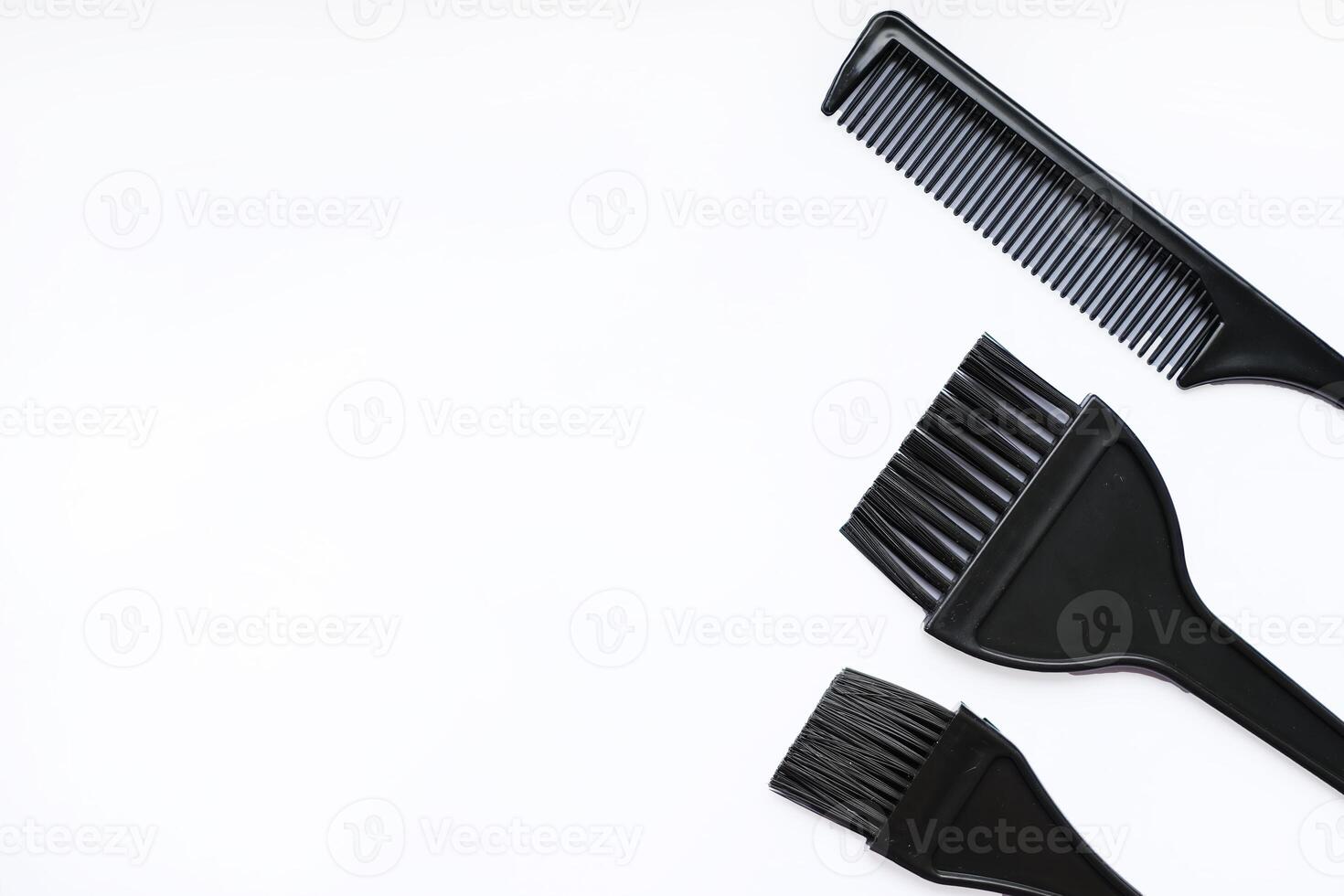 Flat lay of black hair dye brushes and a comb on a white background photo