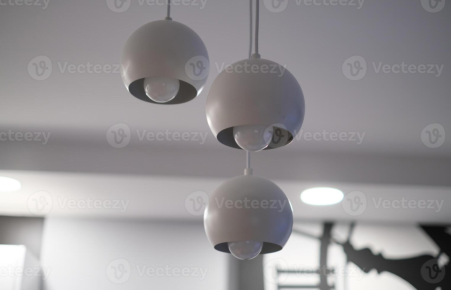 Close-up of three modern pendant lamps with spherical white shades hanging from the ceiling in a minimalistic interior photo