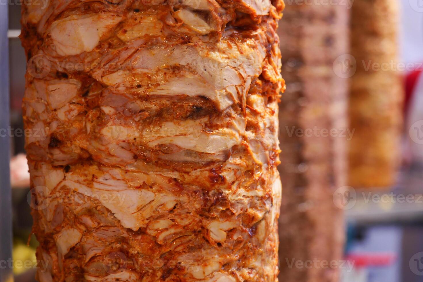 Juicy shawarma meat cooking on rotating spit at a street food stall photo