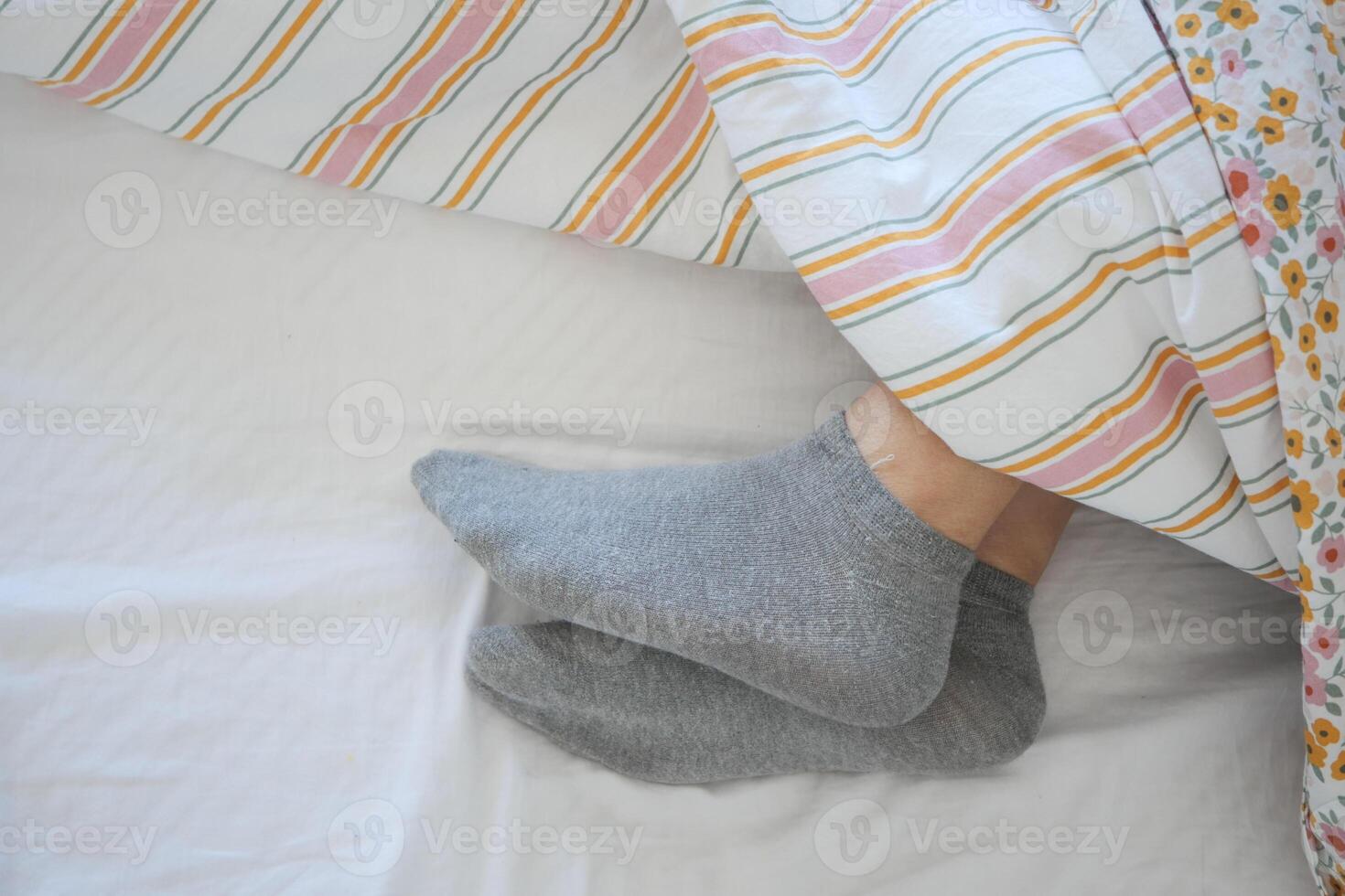 Cozy feet in gray socks under a colorful blanket in morning light photo