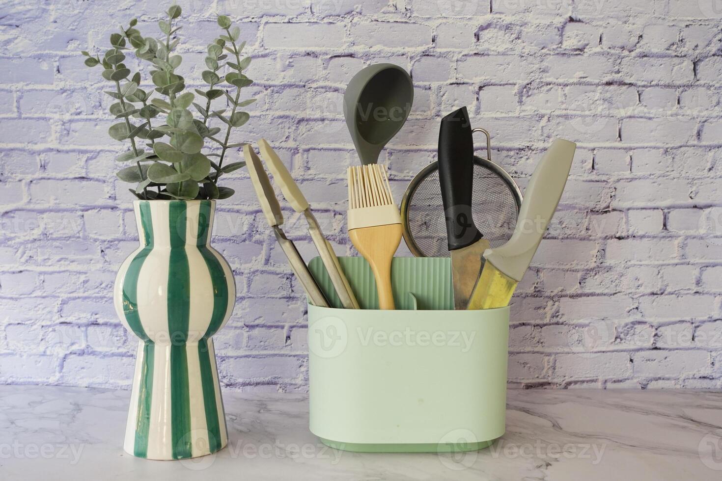 Kitchen tools arranged in pastel container with decorative plant photo