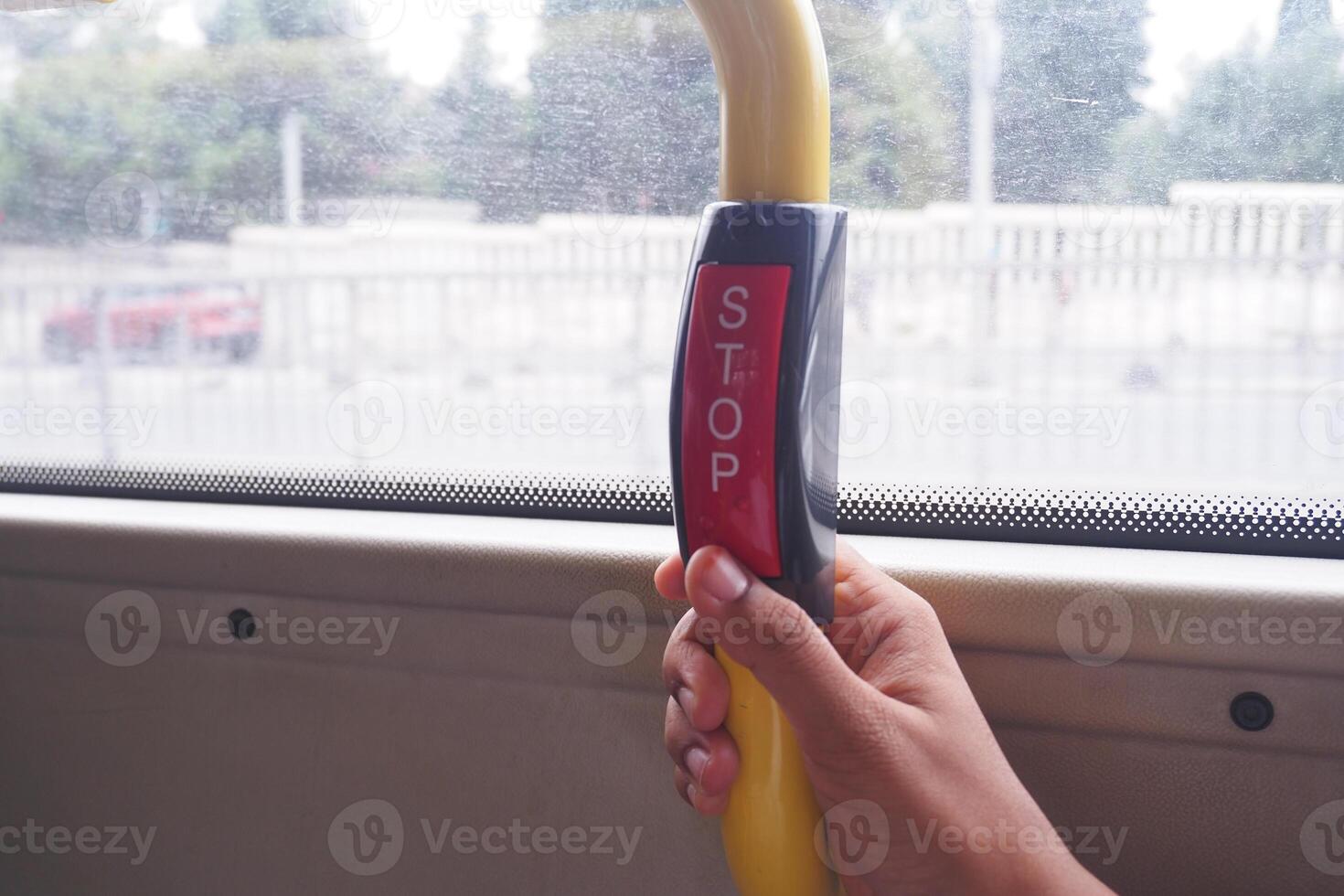Hand presses stop button on bus while commuting in city photo