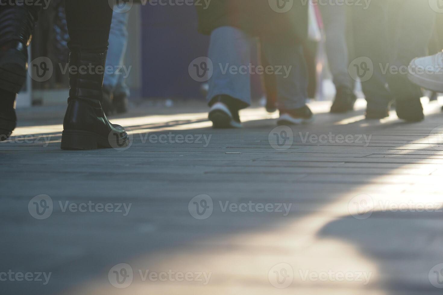 Busy city sidewalk filled with pedestrians during golden hour photo