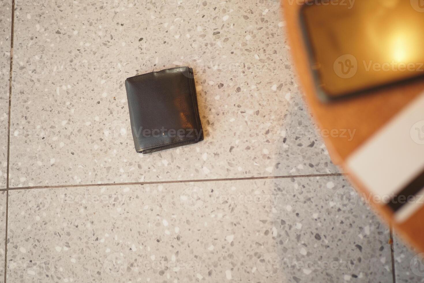 Black wallet dropped on a tiled floor. lost wallet concept photo