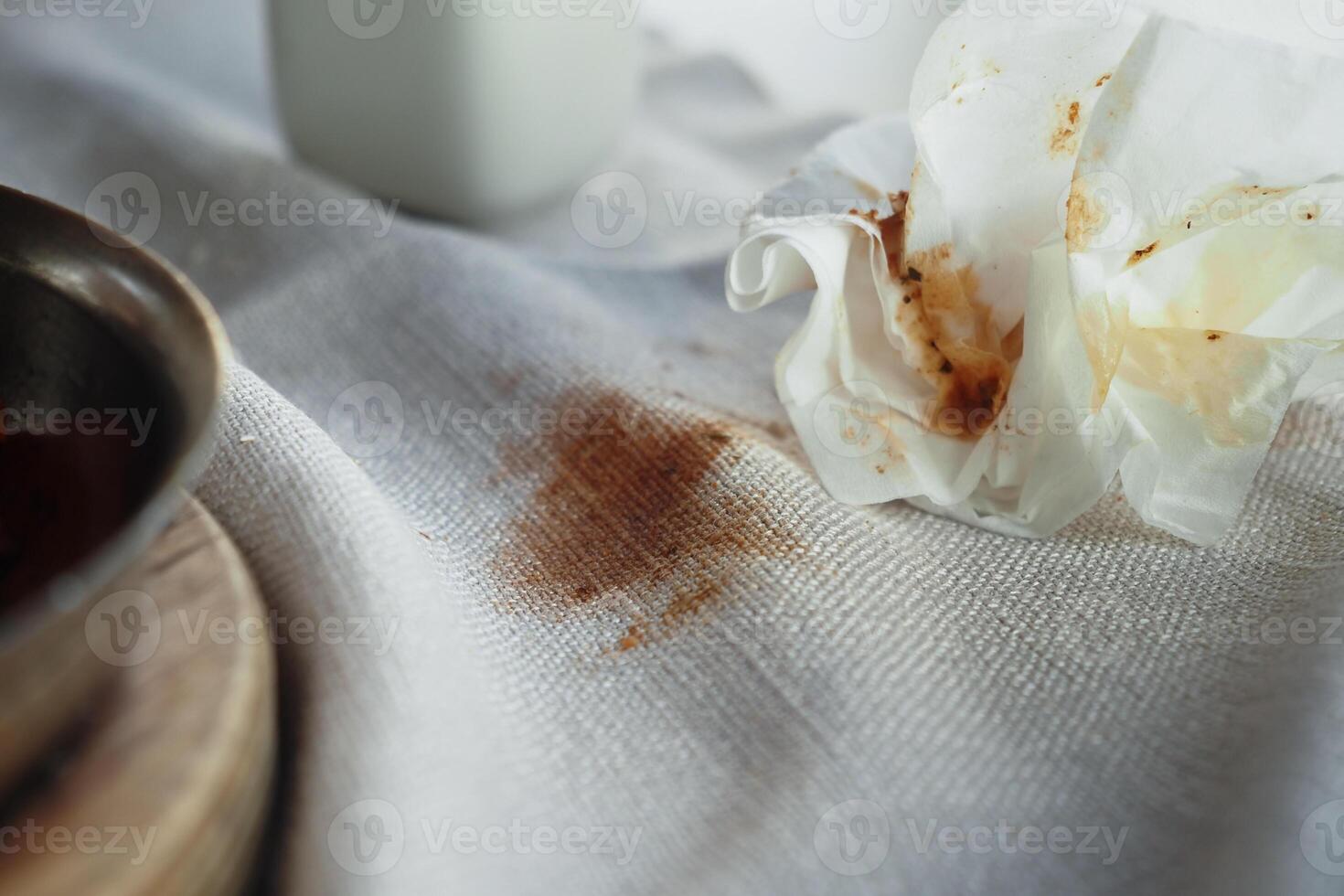 Chocolate stain on white fabric with a crumpled napkin nearby photo