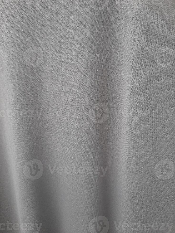 A close-up image of a smooth grey fabric with subtle vertical folds, giving it a soft and elegant appearance. photo
