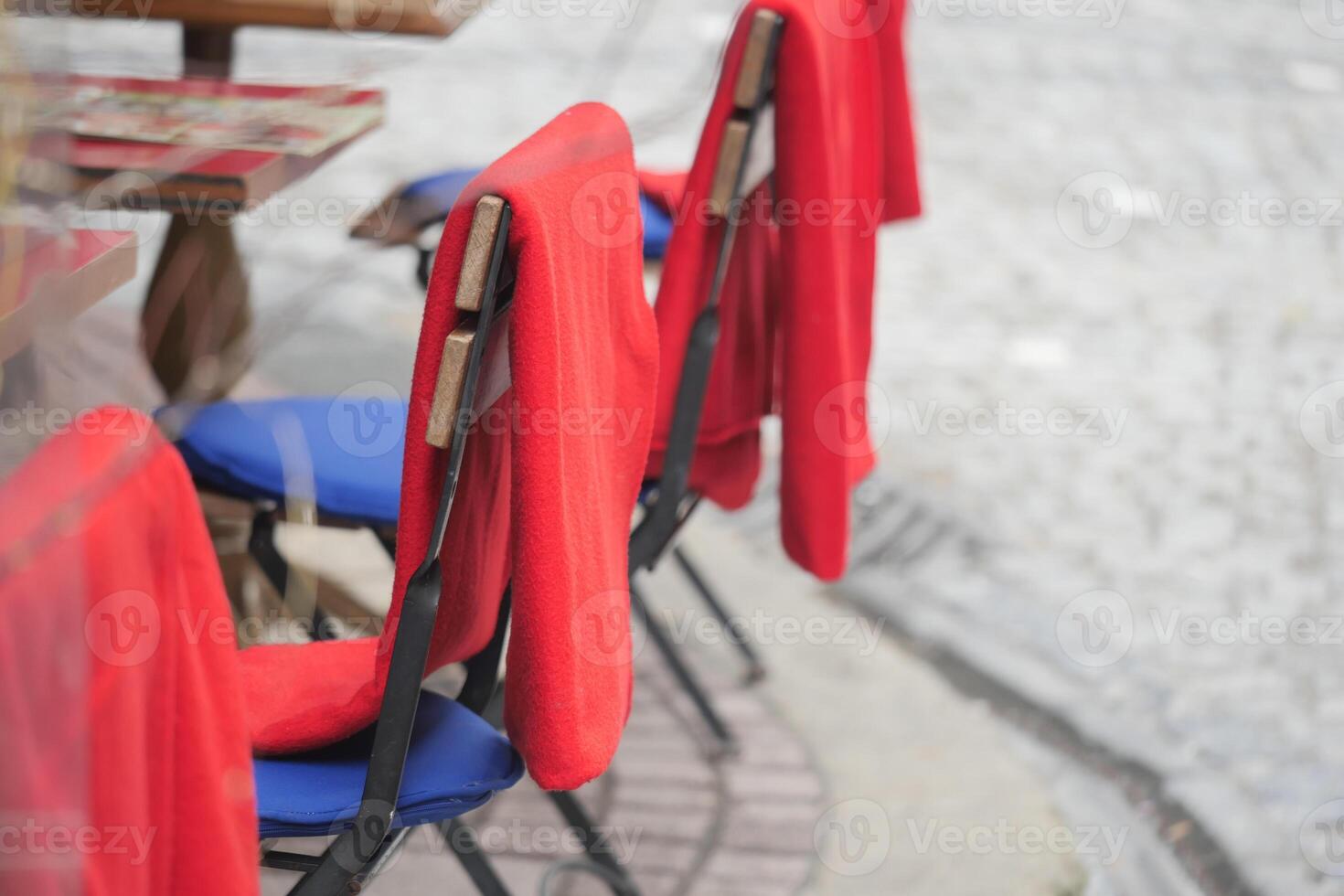 Empty chairs with red covers on a cobblestone street in autumn photo