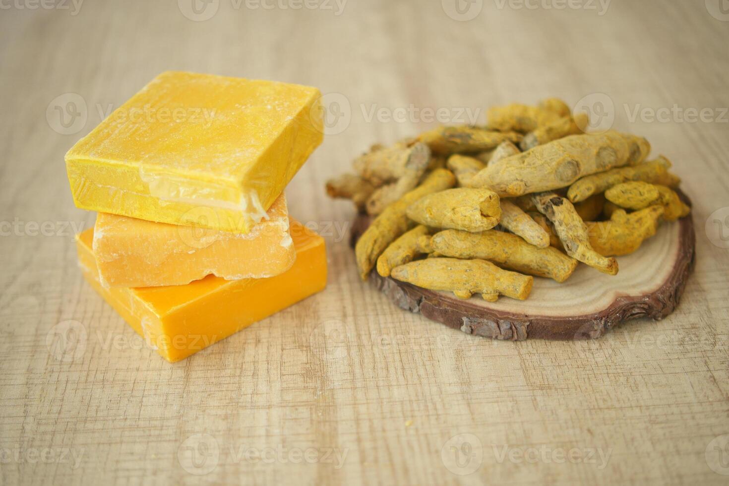 Colorful handmade soaps and natural turmeric roots on wooden table photo