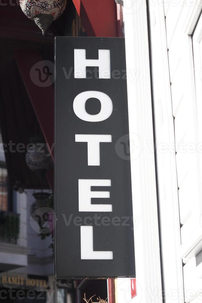 Black hotel sign hanging outside in a busy urban area photo