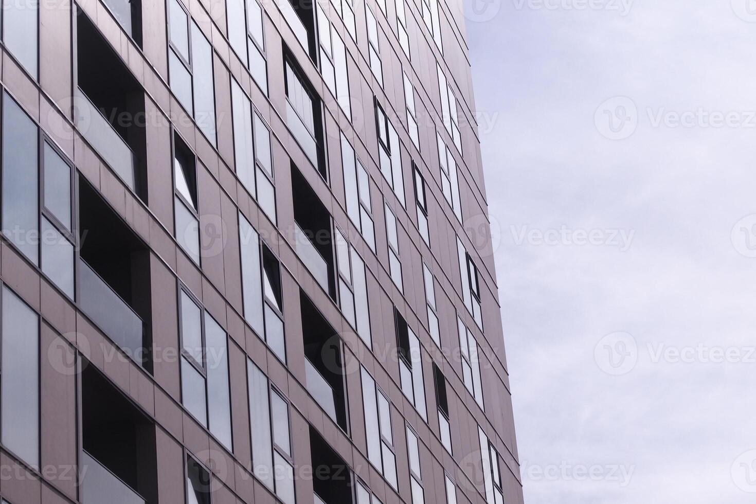 Modern building exterior with reflective windows under cloudy sky photo