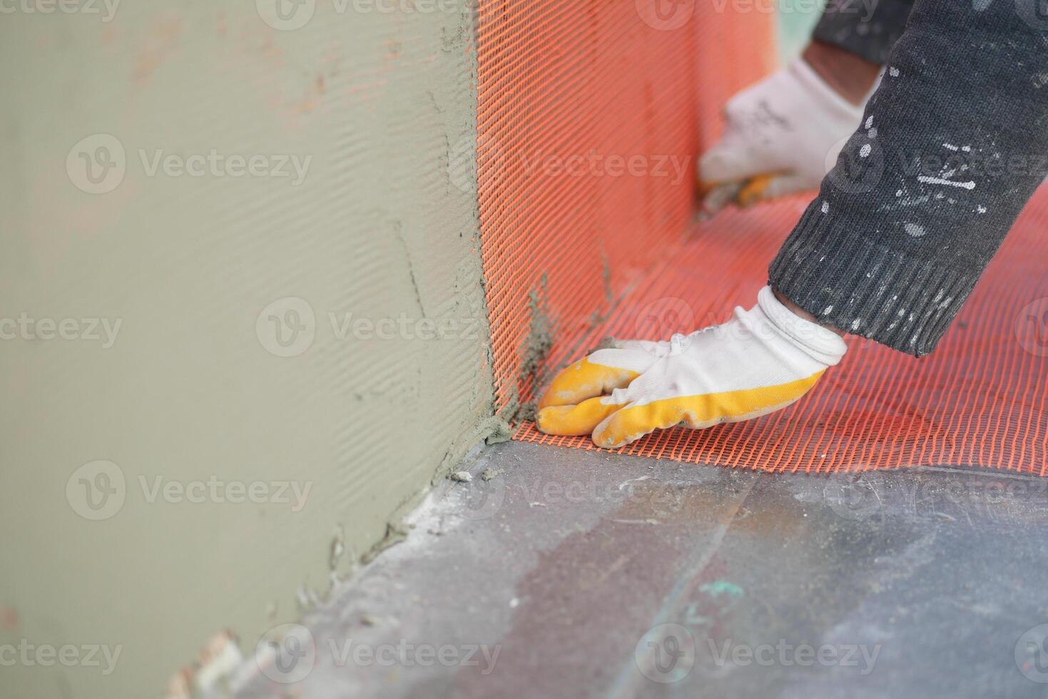 Worker applying mesh for wall reinforcement at construction site photo