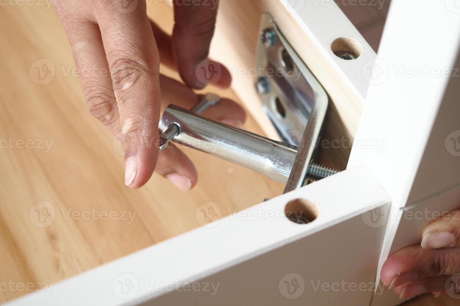 Person assembling furniture with metal connector in a home setting photo