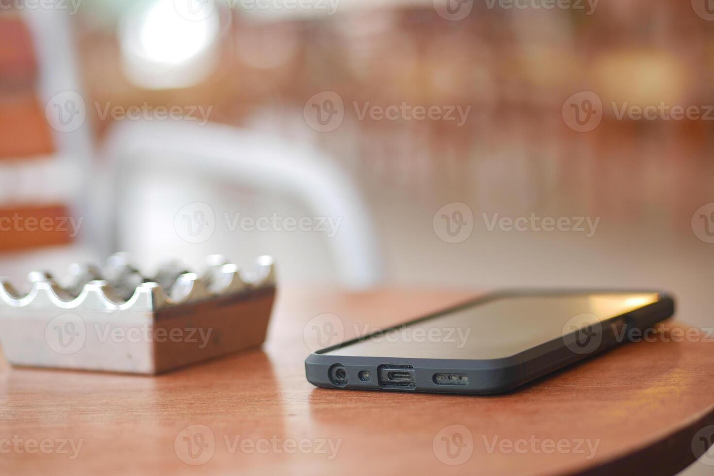 Smartphone resting on a wooden table near an ashtray in a cafe photo
