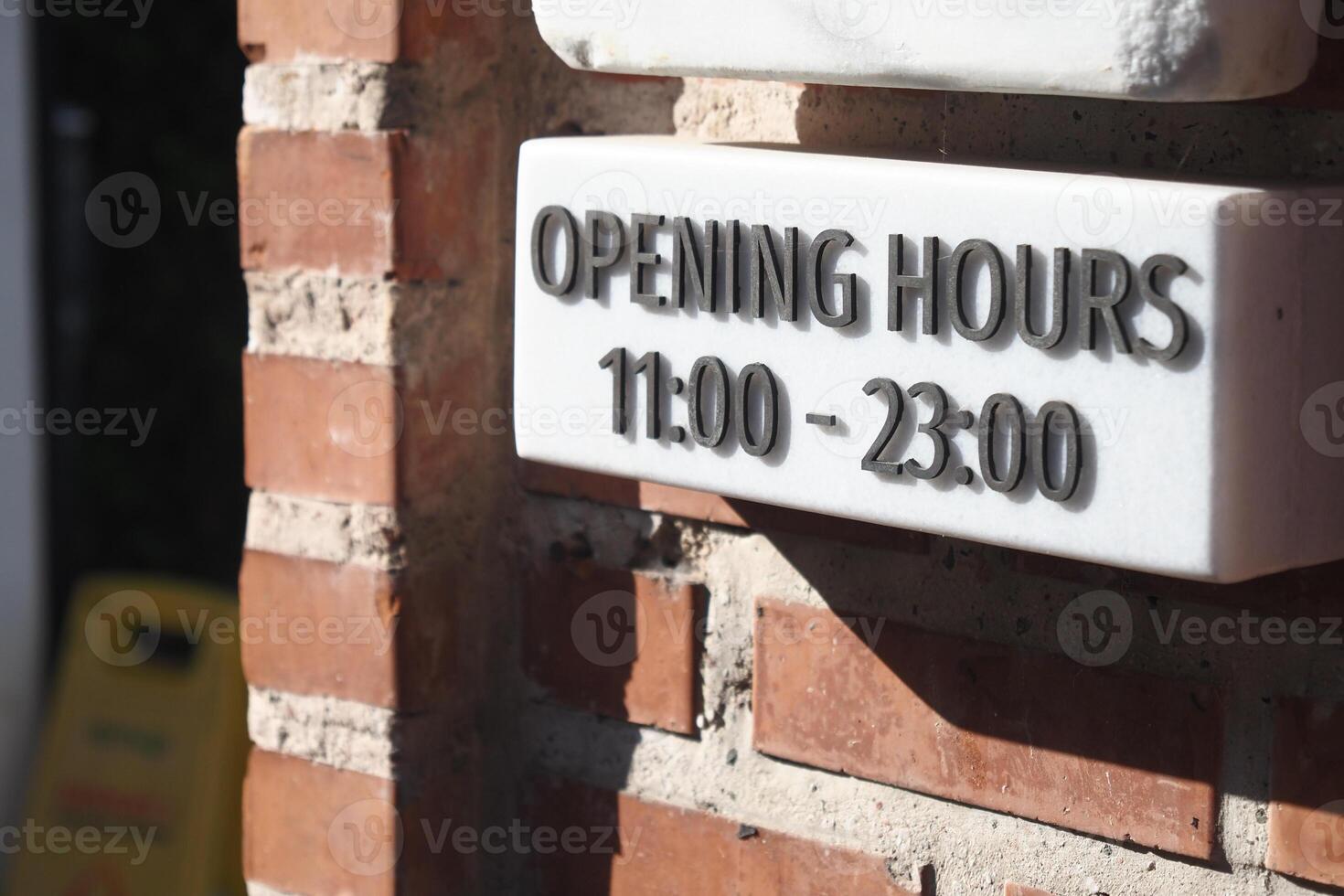 Opening hours displayed on a brick wall at a local establishment photo